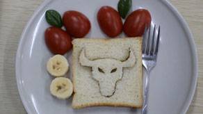 bread slice with a bull-shape cutout with tomatoes and banana on a plate